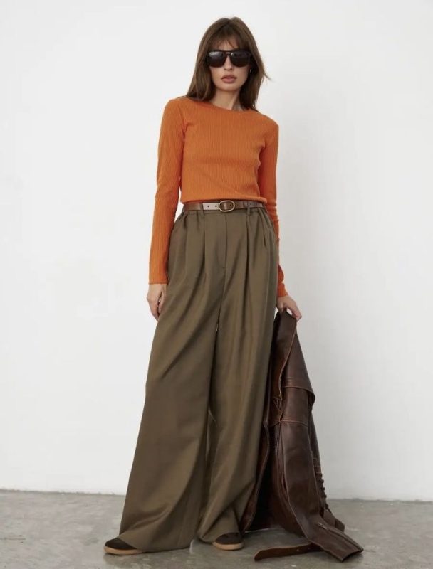 Cô gái mặc áo len cam đất và chân váy nâu, phong cách vintage.