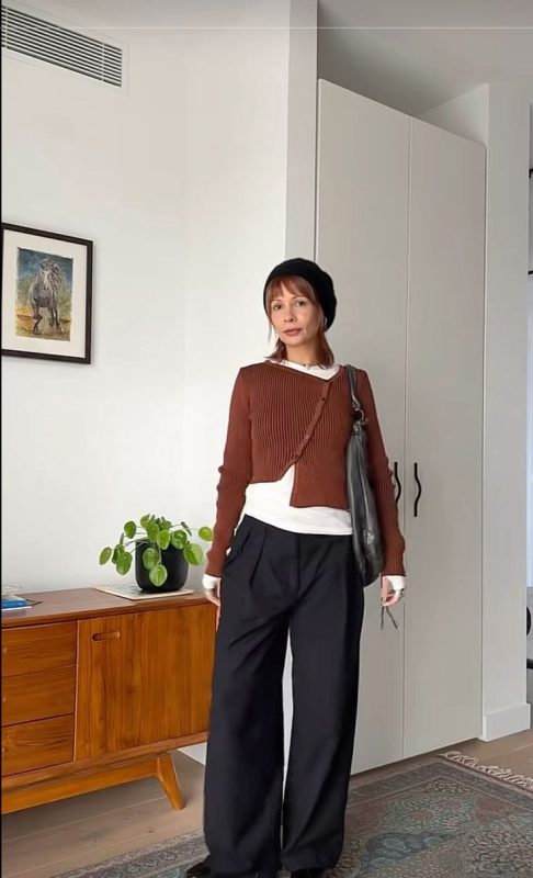 Cô gái mặc áo khoác cam đất và quần đen, phong cách cá tính.