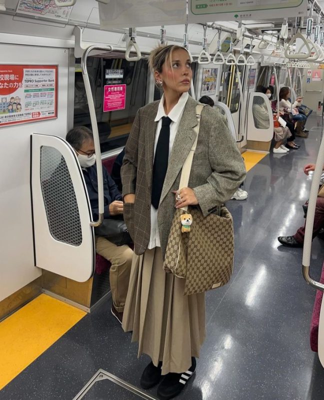 a woman in a suit and tie standing on a subway train